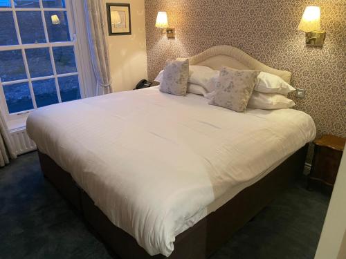 a bedroom with a bed with white sheets and pillows at The Portaferry Hotel in Portaferry