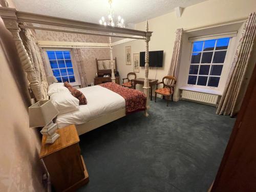 a bedroom with a bed and a desk and two windows at The Portaferry Hotel in Portaferry