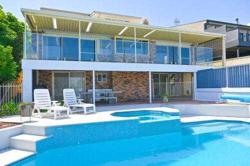 a house with a swimming pool in front of a house at Lakeside Luxury in Gorokan