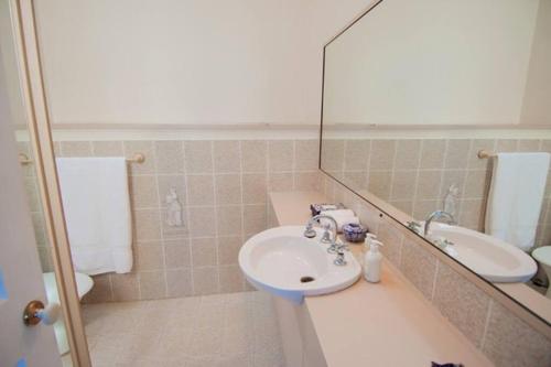 ein Bad mit einem Waschbecken und einem Spiegel in der Unterkunft Lakeside Luxury in Gorokan