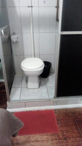 a bathroom with a toilet and a red rug at Pousada Jardim Alameda in Blumenau