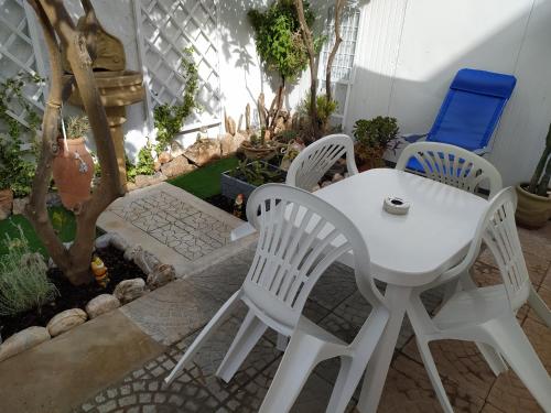 Buggerru Vacanze في بوجيرو: طاولة بيضاء وكراسي في حديقة