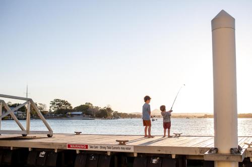 two people standing on a dock fishing on the water at Las Rias Holiday Apartments in Noosa Heads