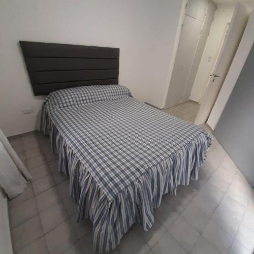 Una cama en una habitación con una manta a cuadros. en Departamento Nueva Cordoba Chacabuco en Córdoba