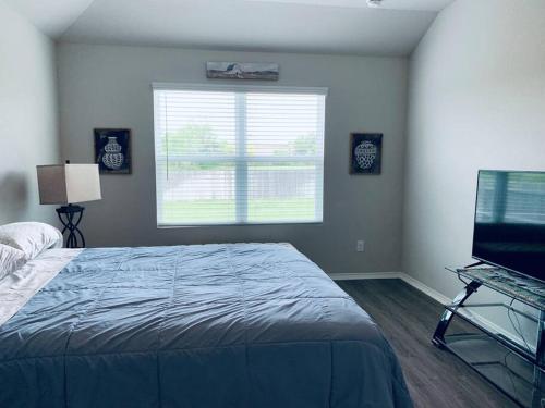 um quarto com uma cama, uma janela e uma televisão em Cheerful three-bedroom home em San Antonio