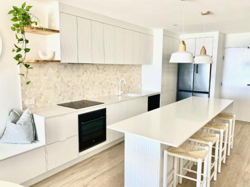 a kitchen with white cabinets and a white counter top at Monterey Lodge - Unit 18, 27 Warne Terrace, Kings Beach Caloundra in Caloundra