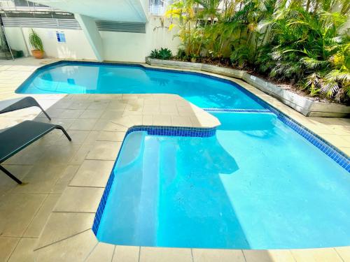 a large blue swimming pool with a chair in the middle at Monterey Lodge - Unit 18, 27 Warne Terrace, Kings Beach Caloundra in Caloundra