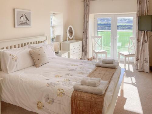 a bedroom with a large white bed with towels on it at Ardstinchar Mews in Ballantrae