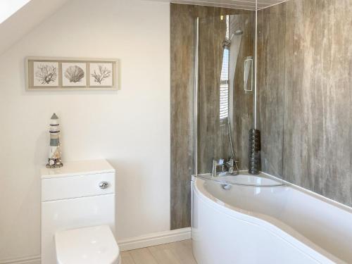 a white bathroom with a tub and a toilet at Ardstinchar Mews in Ballantrae