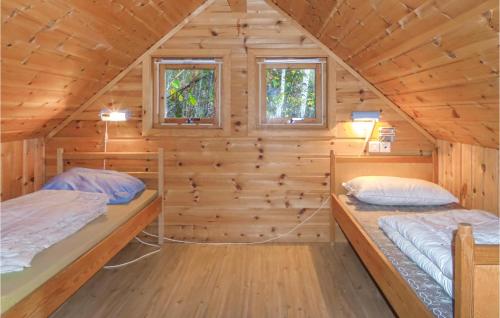 two beds in a log cabin with two windows at Amazing Home In Vallavik With House Sea View in Vangsbygd