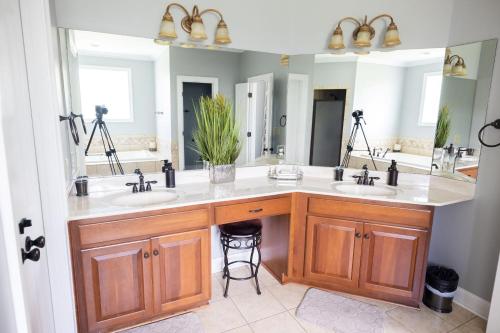 a bathroom with two sinks and two mirrors at SoulBeatz Country Mini Mansion w/ Pool & Putting Green in Hope Hull