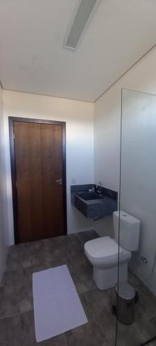 a bathroom with a toilet and a wooden door at Mangabeiras - Casa de Hóspedes in Alto Paraíso de Goiás