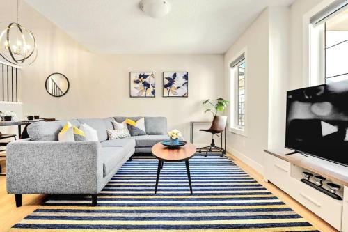 a living room with a couch and a tv at Stylish 3BR Townhouse by Airport in Calgary