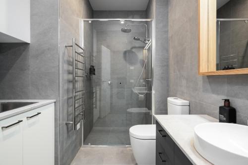 a bathroom with a shower with a toilet and a sink at Sheppard Art House Townhouse in Bright