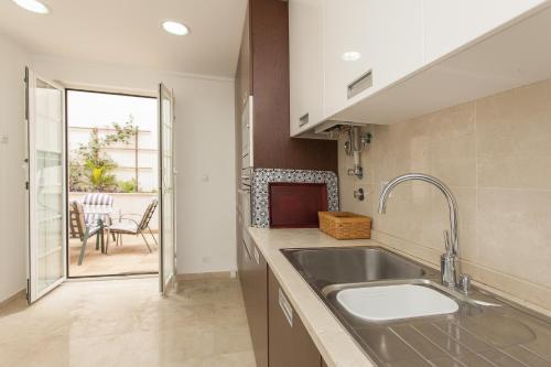 a kitchen with a sink and a view of a patio at Bairrus Lisbon Apartments - Alfama II in Lisbon