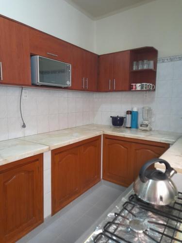 cocina con armarios de madera y tetera de plata en Preciosa Casa Centrica y Acogedora, en Tarija