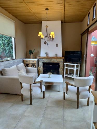 sala de estar con sofá, sillas y chimenea en La Casa de Ale en Tandil