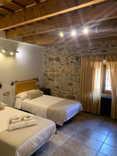 a bedroom with two beds and a stone wall at Habitaciones Rurales La Vertedera I in Villar de Ciervo