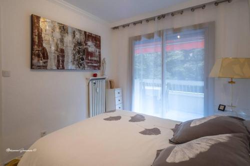 een witte slaapkamer met een bed en een raam bij Ô 27 Fleurie Cannes in Cannes