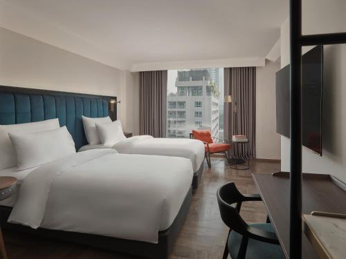two beds in a hotel room with a large window at Public House Hotel - Sukhumvit 31 in Bangkok