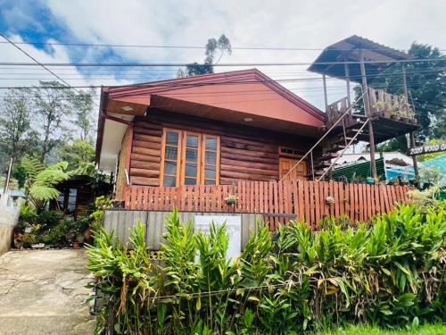 une maison en bois avec une clôture devant elle dans l'établissement 20/20 wood cabana, à Nuwara Eliya