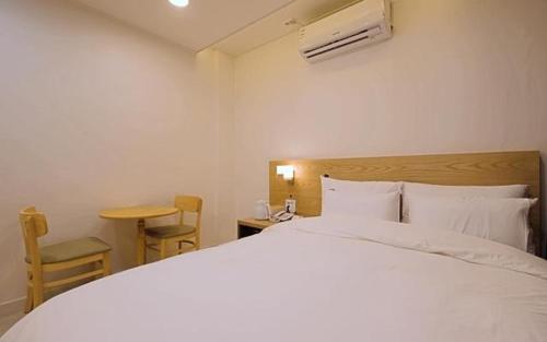 ein Schlafzimmer mit einem weißen Bett, einem Tisch und einem Stuhl in der Unterkunft Pier26 Hotel in Pohang