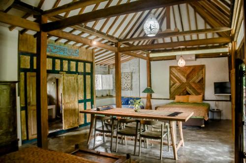 a room with a wooden table and a bed at Villa Nextdoor Nature Yogyakarta in Bantul