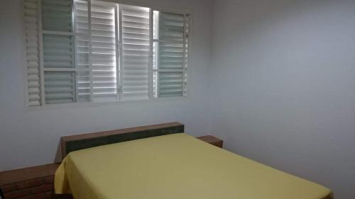 Bett in einem Zimmer mit Fenster in der Unterkunft Rancho Espelho D'água in Capitólio