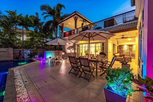 a house with a patio with tables and umbrellas at 3 Bedroom Pool Villa in Great Location STV in Hua Hin
