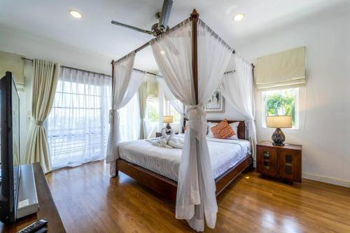 a bedroom with a canopy bed with a ceiling fan at 3 Bedroom Pool Villa in Great Location STV in Hua Hin