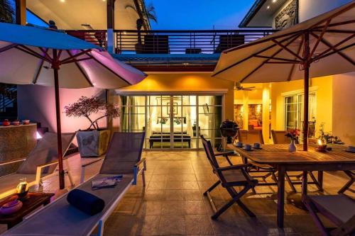 a patio with a table and chairs and umbrellas at 3 Bedroom Pool Villa in Great Location STV in Hua Hin