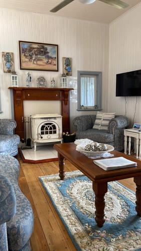 a living room with a coffee table and a fireplace at Cherry Blossom Cottage-with country charm and spa in Stanthorpe