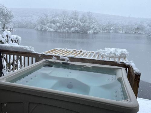 a hot tub on a deck with snow on it at Large family house on the lake in Hewitt
