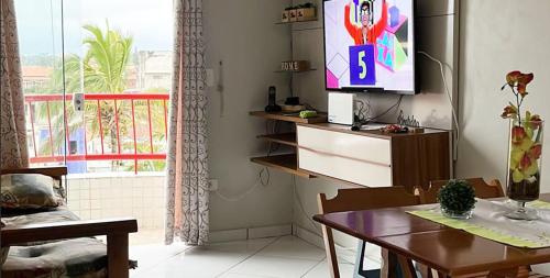 uma sala de estar com uma mesa e uma televisão na parede em Apartamento Pé na Areia em São Bernardo do Campo