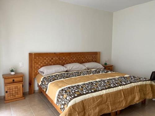 een slaapkamer met een groot bed met een houten hoofdeinde bij Casa Colibri Oaxaca in Santa María Azompa