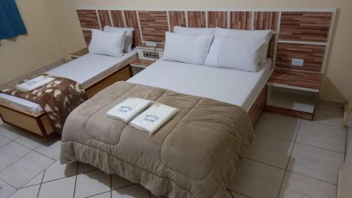 a bedroom with two beds with towels on them at Hotel Dalias in Guarulhos