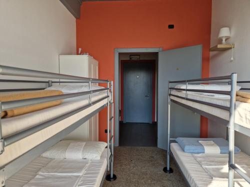 a room with three bunk beds and an orange wall at B&B e Ostello, Parco di Monza, CASCINA COSTA ALTA in Monza