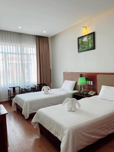 a hotel room with two beds and a table at Bình Minh Hotel in Ha Tinh