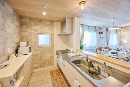 a kitchen with a sink and a microwave at ペンション マカナレアリゾート沖縄 in Ginowan