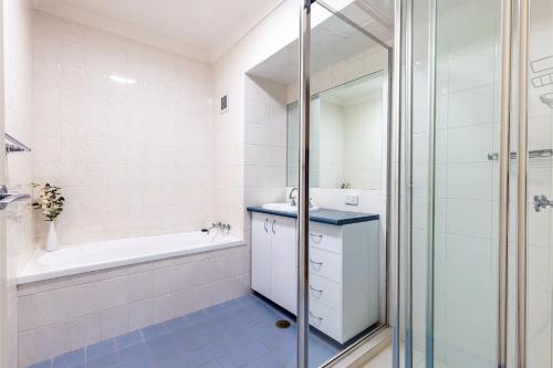 Un baño con bañera, lavabo y ducha. en Florentine 14 - 11 Columbia Close Aircon Wifi unsurpassed water views, en Nelson Bay