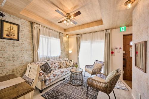 a living room with a couch and chairs at ペンション マカナレアリゾート沖縄 in Ginowan