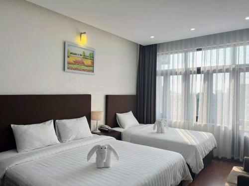 a hotel room with two beds and a window at Bình Minh Hotel in Ha Tinh