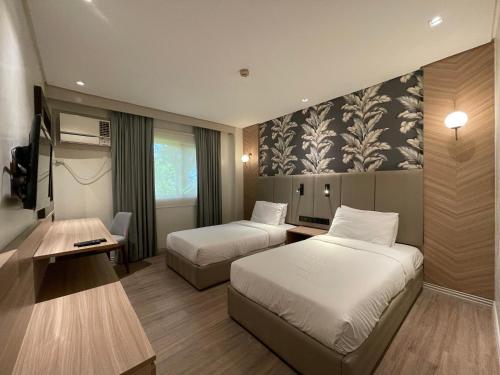 a hotel room with two beds and a desk at Luisita Central Park Hotel in Tarlac