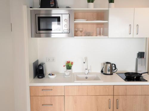 a kitchen with a sink and a microwave at Deluxe Suite - Parking - Workspace in Gießen