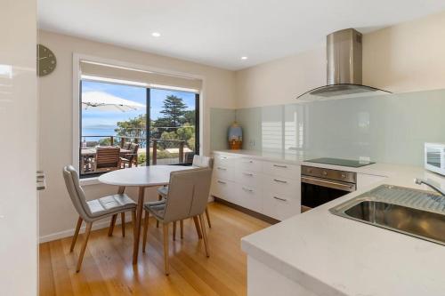 a kitchen with a table and chairs and a window at 'The Alonnah' Beach House - Main House Only in Alonnah