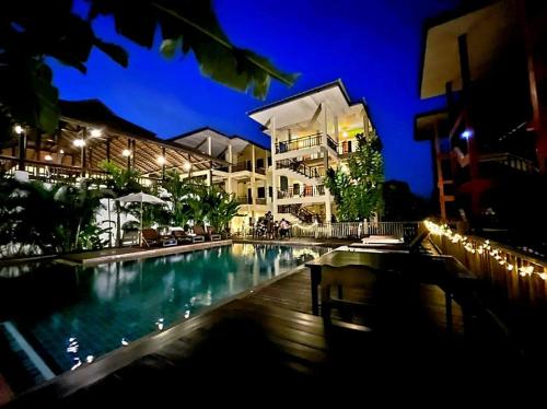 a swimming pool in front of a building at night at Rainforest Huahin Village Hotel in Hua Hin