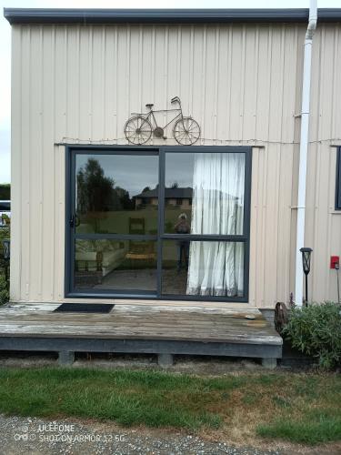 a bike sitting on the window of a house at Flying Plate Saloon in Waimate