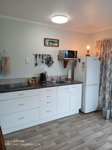 a kitchen with white cabinets and a refrigerator at Flying Plate Saloon in Waimate