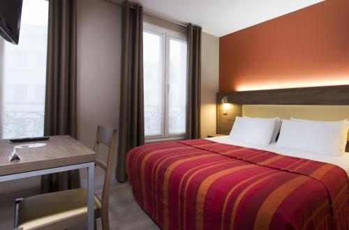 a hotel room with a bed and a table and a desk at Hôtel des Pavillons in Paris