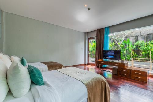 a bedroom with two beds and a flat screen tv at The Leaf Jimbaran in Jimbaran